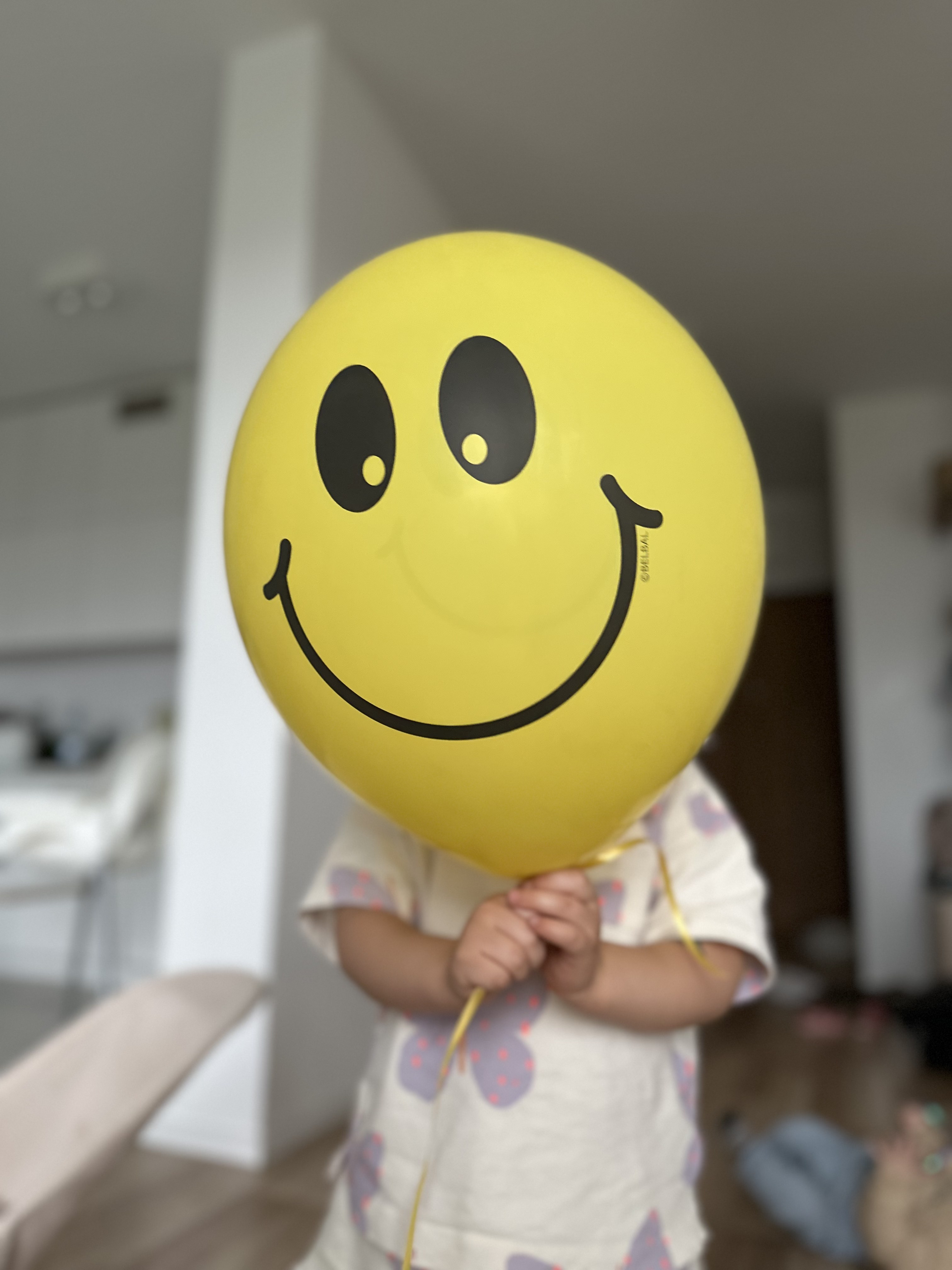 Dziecko trzyma żółty balon z uśmiechem przed twarzą — symbol oswojonego strachu
